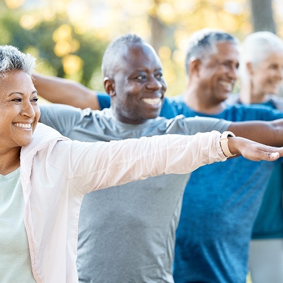 Diverse group of older adults smiling doing yoga in the forest