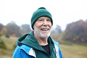 Senior man with wool hat standing outside and smiling